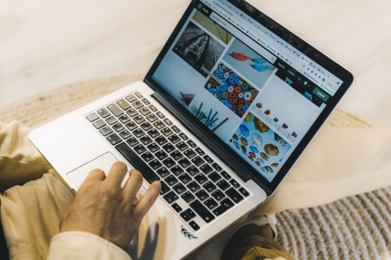 Persoană cu laptop și hârtii pe masă, făcând planuri pentru o idee nouă